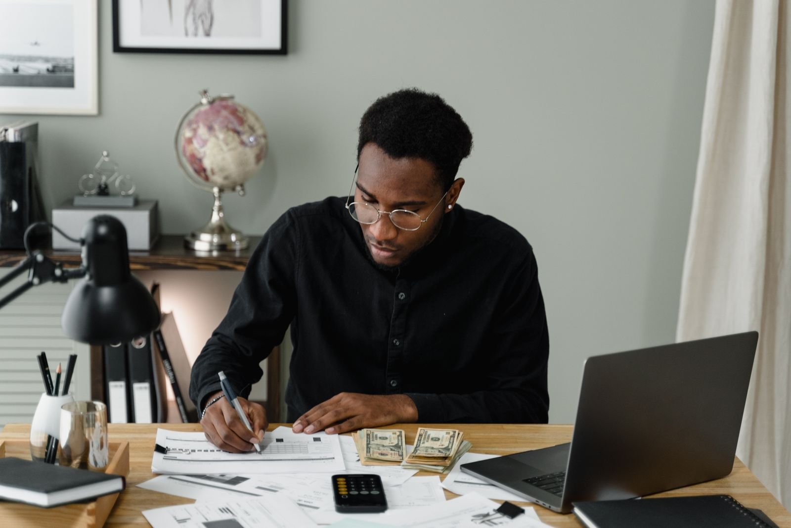Person working through financial documents with a calculator and laptop