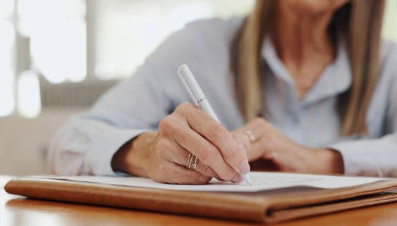 Hands filling in a printed government job application form with a pen